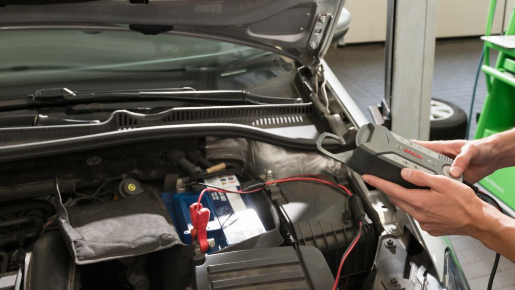 Mekaniker utför batterikontroll på bil med Bosch Car Service utrustning